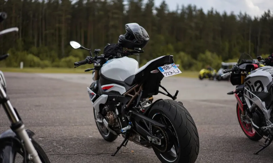 Débutant en équipement moto à côté d'une petite cylindrée, parking ensoleillé